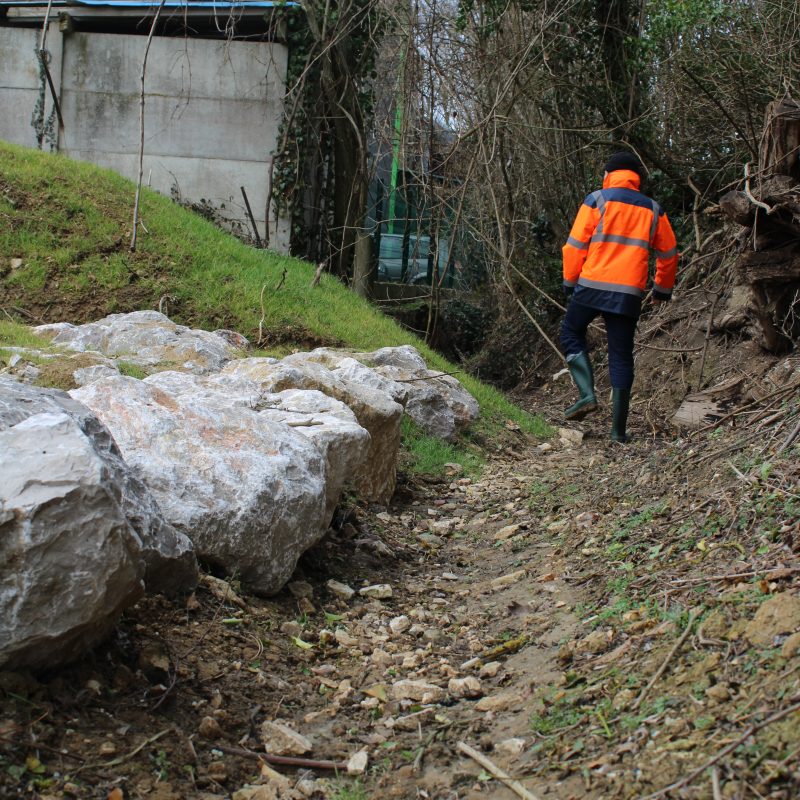 Un cours d'eau à sec avec un homme en veste orange marchant dedans
